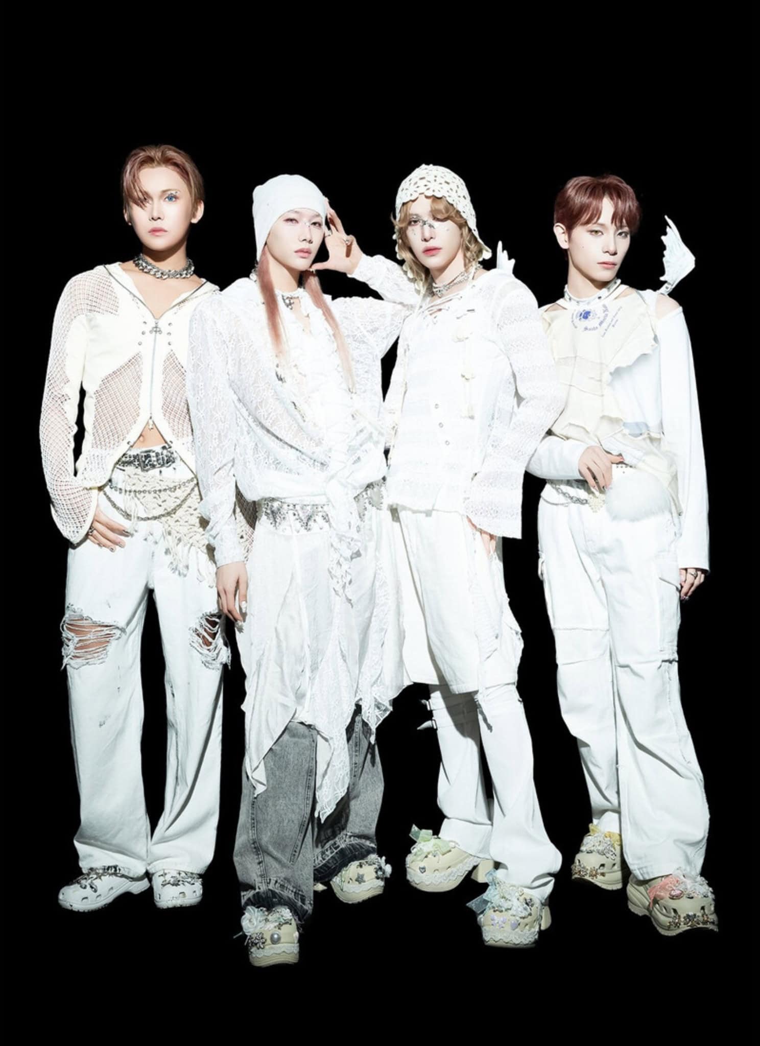 Four people stand against a black background wearing stylish, all-white XLOV outfits with varied textures like mesh and lace, plus layered accessories. Their expressions are serious and their hair is styled fashionably.