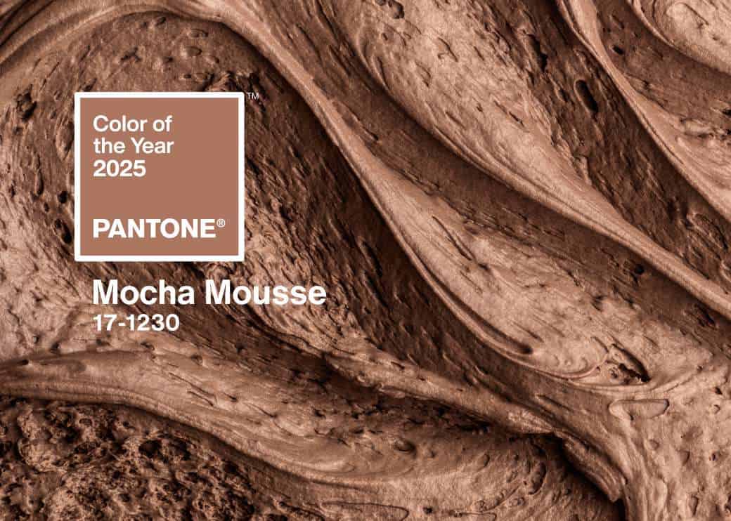 Close-up of rich, swirled chocolate-brown texture with text: Color of the Year 2025, PANTONE Mocha Mousse 17-1230. The background resembles smooth, creamy chocolate mousse.