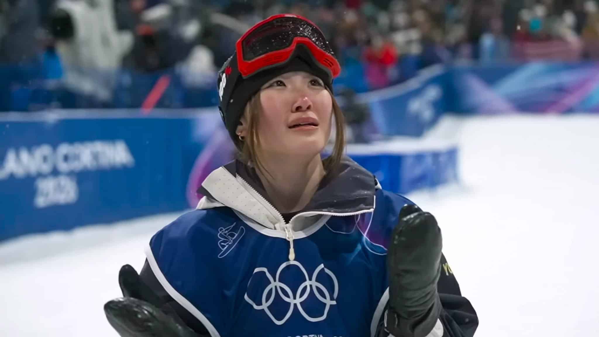 A woman wearing a blue jacket and black hat with red goggles.