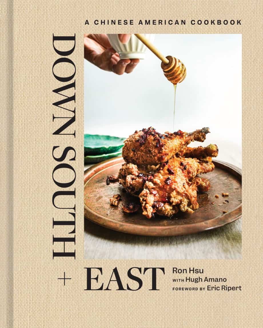 The cover of the cookbook Down South + East features fried chicken stacked on a plate, drizzled with honey from a dipper. The background is light with the title and author names displayed prominently.