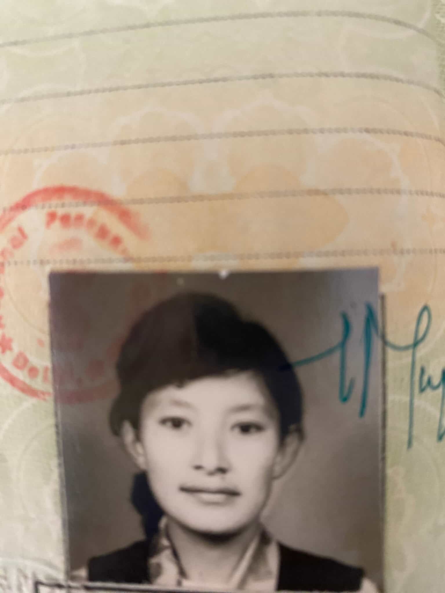 A close-up photo of an identification document featuring a black-and-white portrait of a young person with short, dark hair. The document has a faint patterned background and a partially visible red stamp.