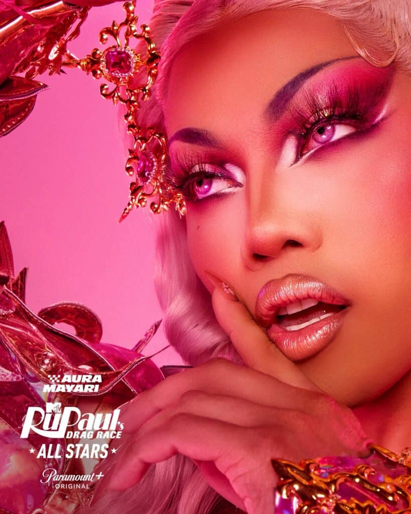 Close-up of a drag queen with dramatic pink eye makeup, long lashes, nude glossy lips, and platinum-blonde hair adorned with ornate pink and gold accessories. RuPaul’s Drag Race All Stars and Paramount+ logos appear in the corner.