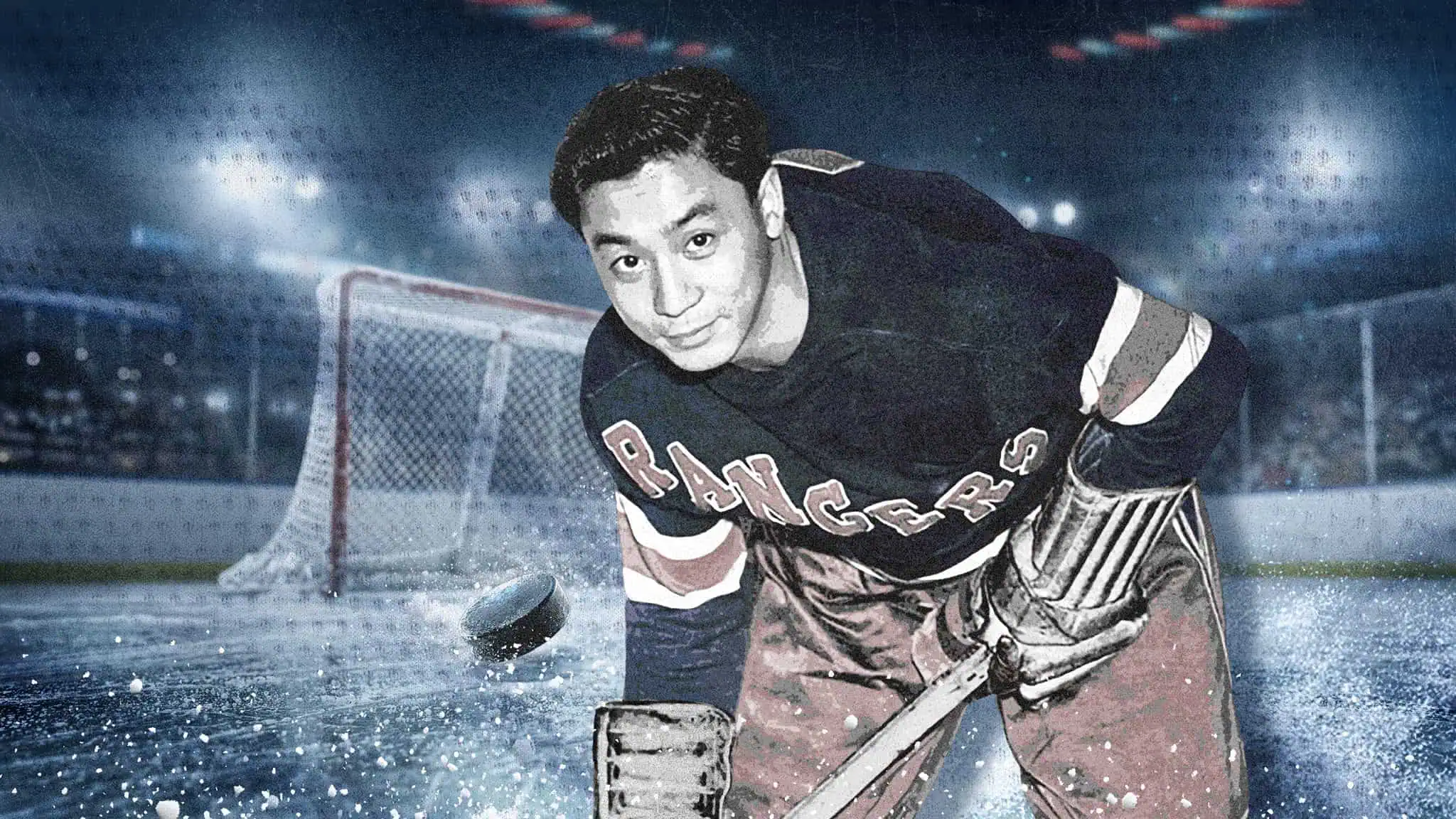 A hockey player wearing a Rangers jersey stands on the ice in front of a goal net, holding a stick and looking at the camera, with a puck and ice particles in the foreground.