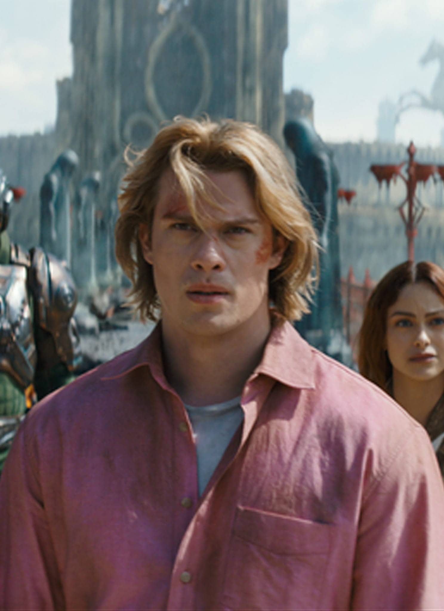 A young man in a pink shirt stands in front of a woman, armored figures, and a green tiger, with a fantasy city featuring statues and ruins in the background under a bright sky.