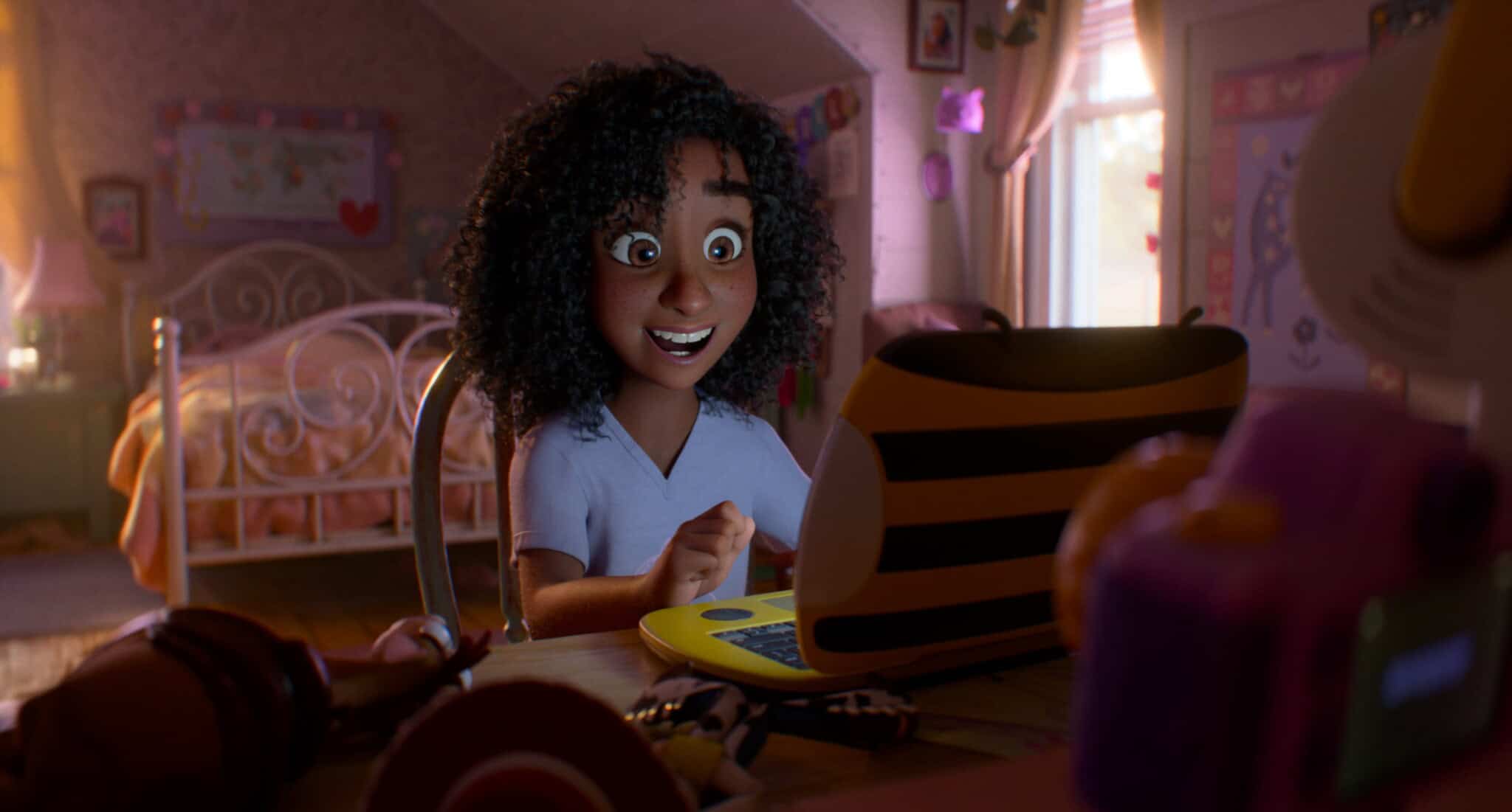 A smiling animated girl with curly hair sits at a desk in her bedroom, looking excitedly at a yellow laptop with black stripes. The room is cozy and warmly lit, with toys and decorations visible in the background.