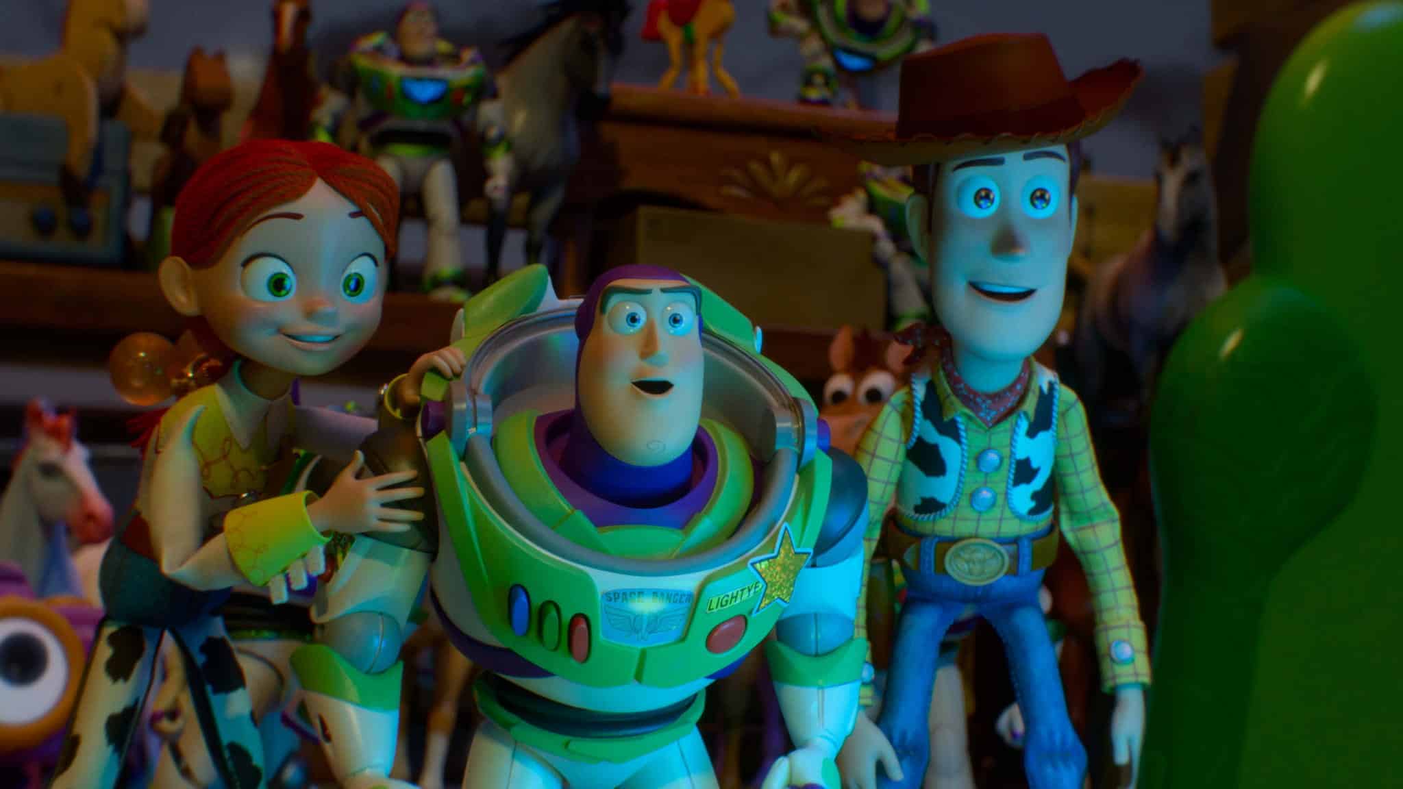 Three animated toy characters—a cowgirl, a space ranger, and a cowboy—stand together looking ahead with excited expressions. Other toy figures and colorful objects are visible in the background.