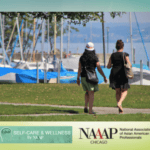 Two women walk along a path in a park on a sunny day, with sailboats and water in the background. Logos for NAAAP Chicago and “Self-Care & Wellness by NAAAP” appear at the bottom of the image.