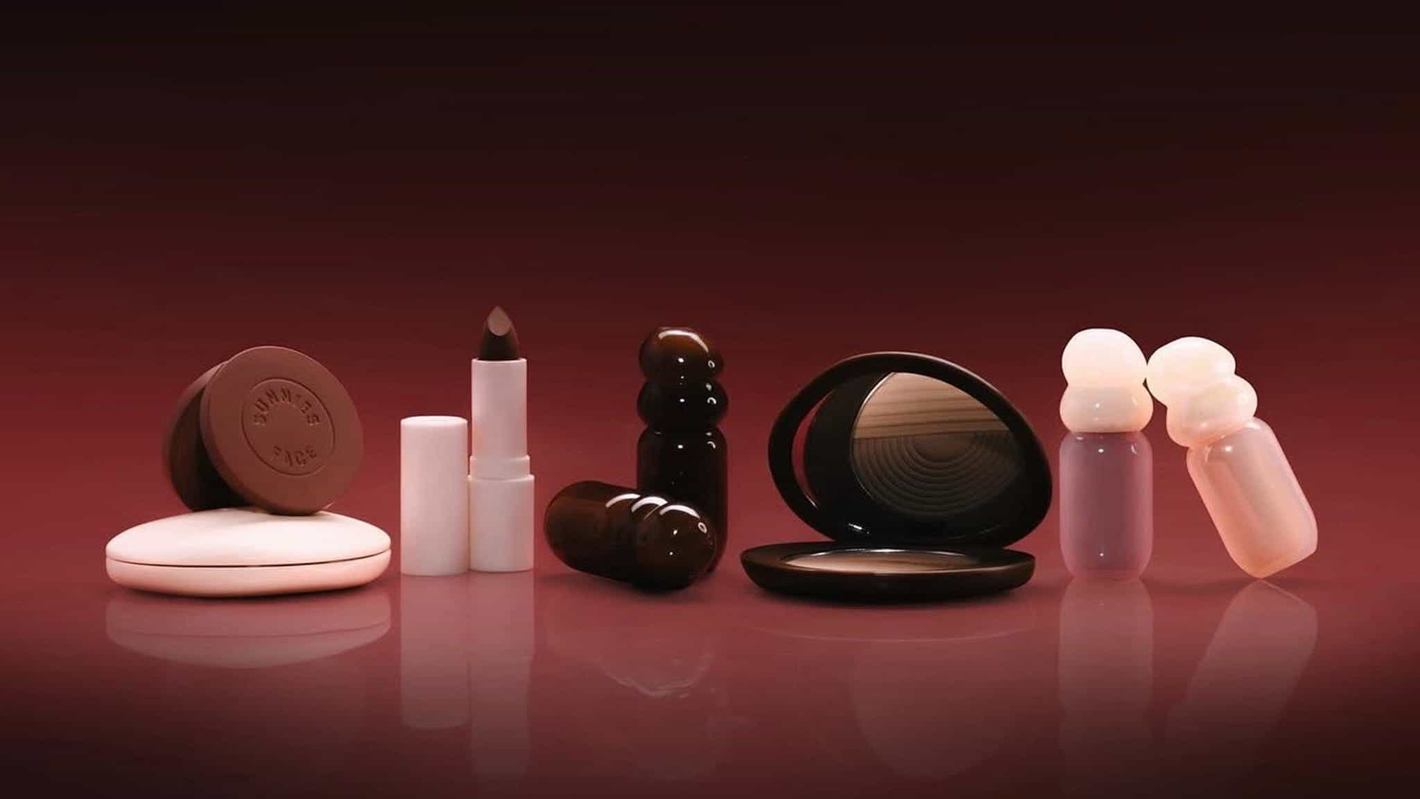 A set of various makeup products including lipstick, compacts, and bottles, arranged neatly against a gradient burgundy background.