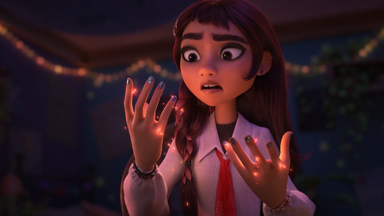 Animated girl with long brown hair looks at her glowing hands in shock. She wears a white shirt with a red tie, and string lights are blurry in the background. Her fingers emit small orange sparkles.
