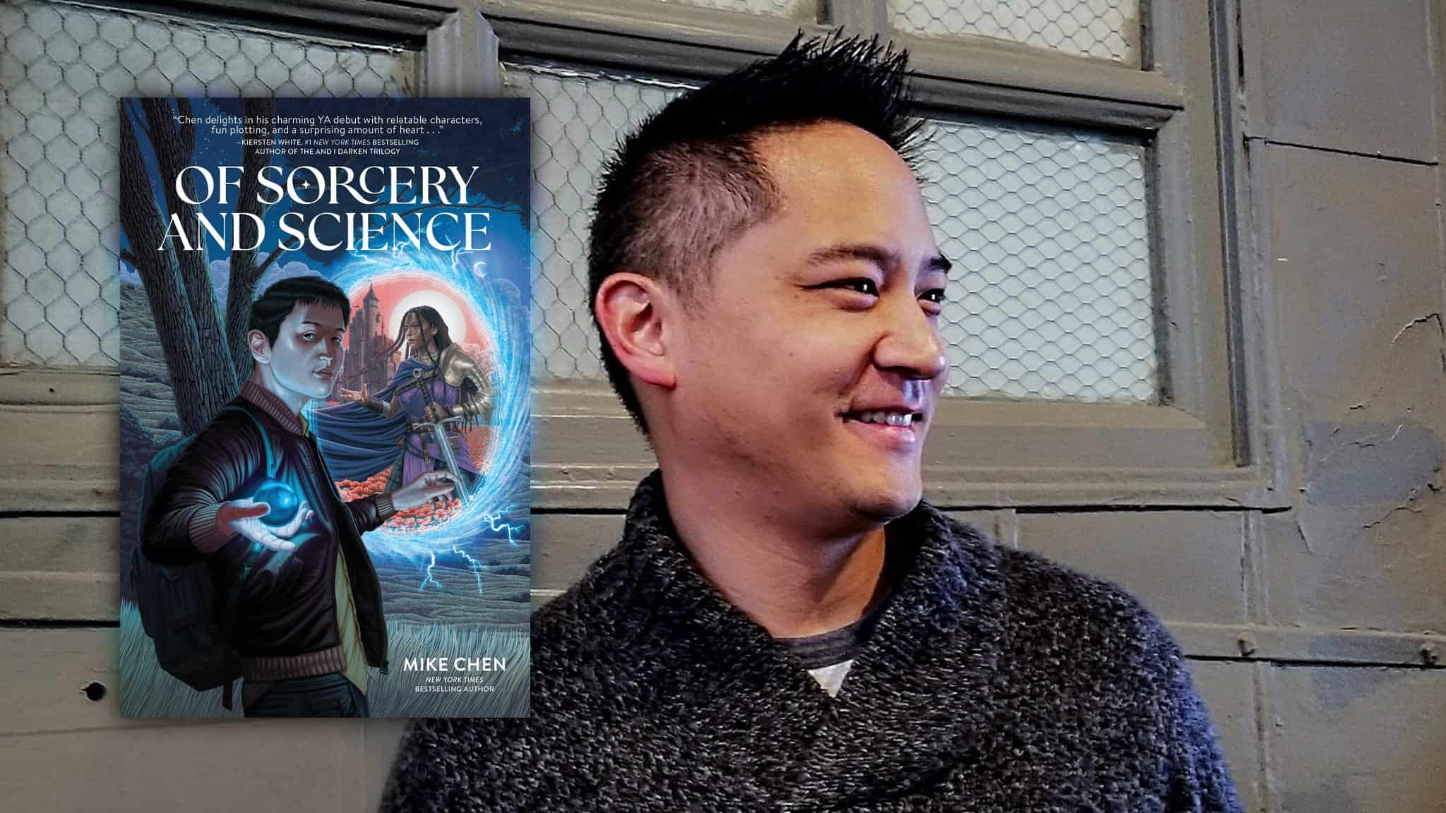 A smiling man in a gray sweater stands in front of a window. Next to him is the cover of the book Of Sorcery and Science by Mike Chen, featuring a young man holding a glowing device and a woman with magical energy.