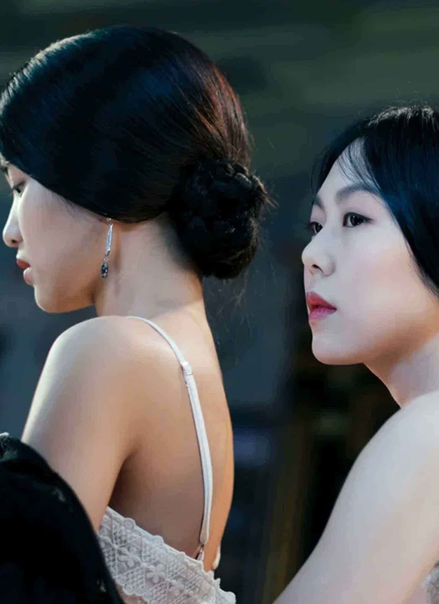Two women with dark hair styled in buns looking in different directions.