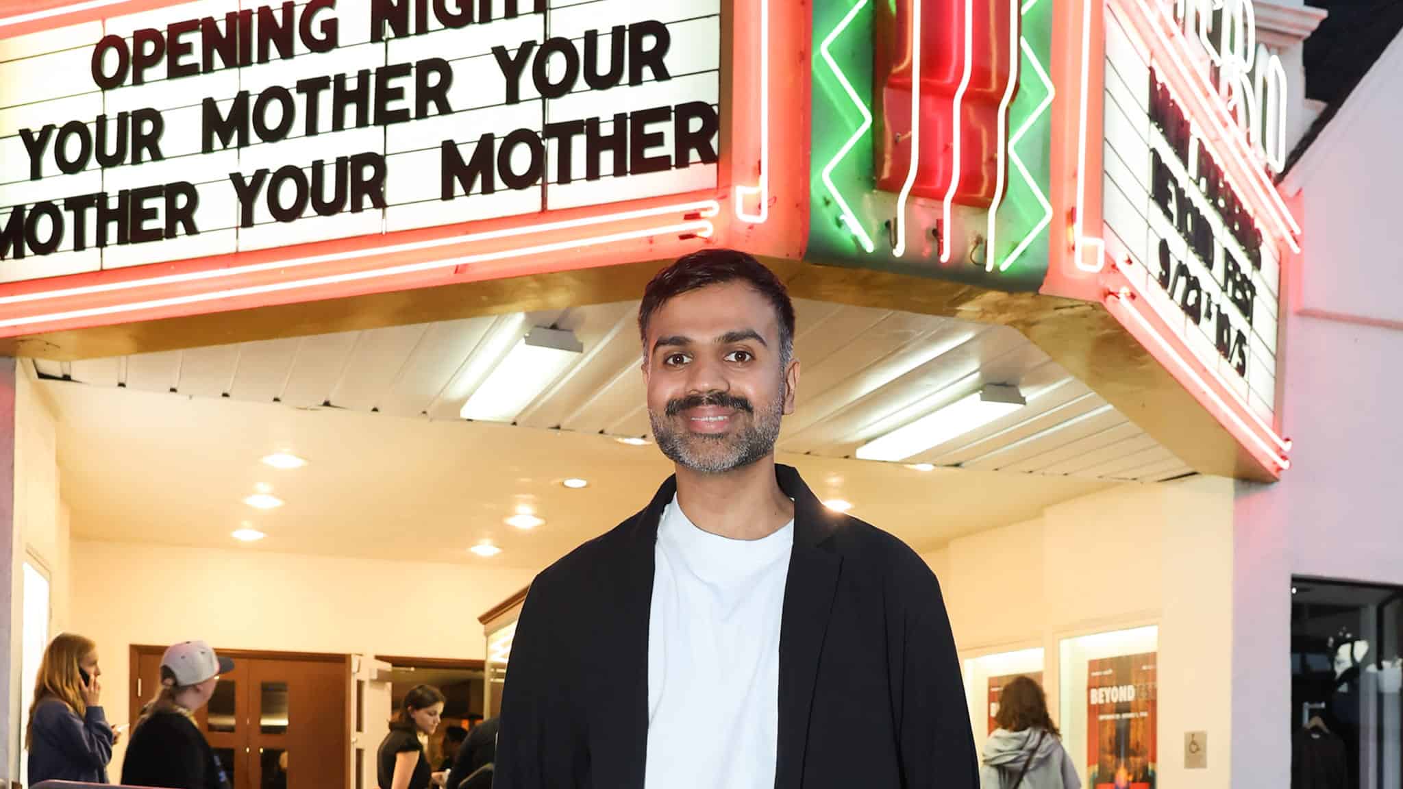 A man smiling in front of a theater marquee that reads Opening Night Your Mother Your Mother Your Mother.