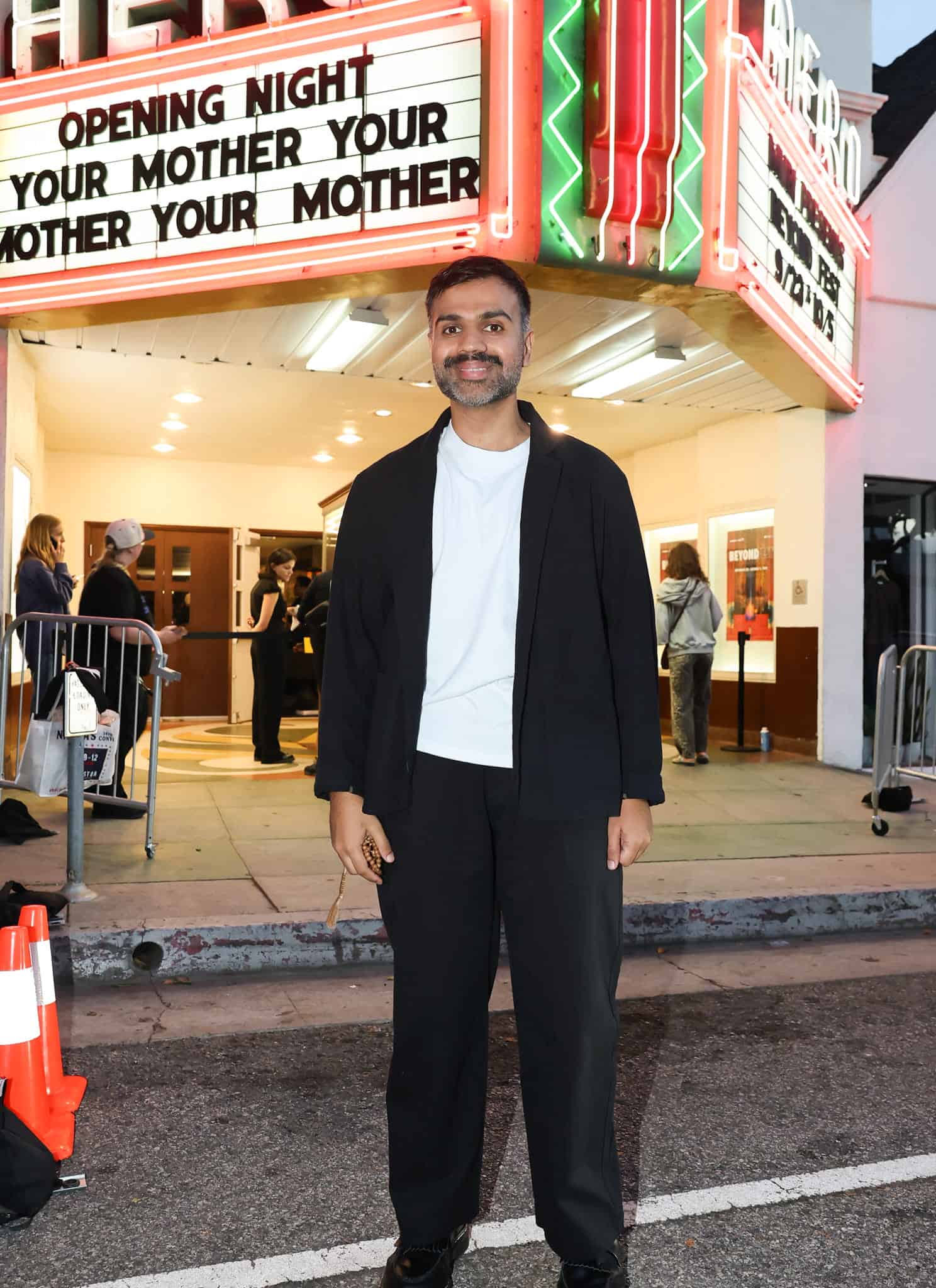 A man smiling in front of a theater marquee that reads Opening Night Your Mother Your Mother Your Mother.