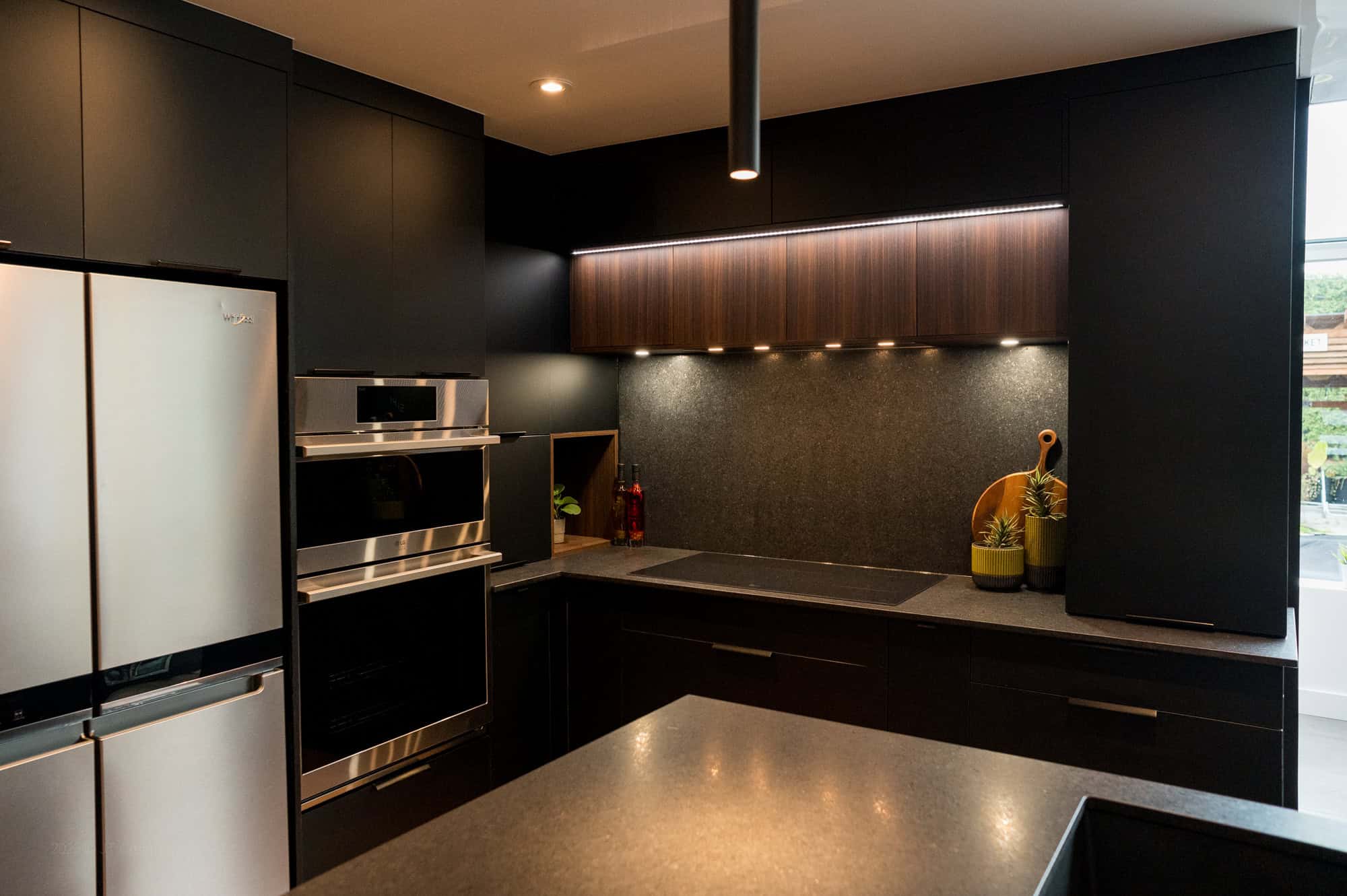 Cuisine noire avec armoires pleine hauteur et bandeau de bois éclairé — réalisation JT Création