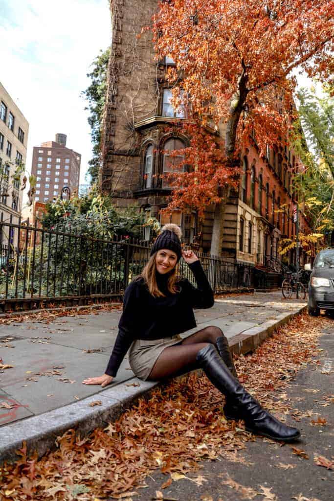 girl sitting on a curb with fall foliage at stuyvesant street in New York