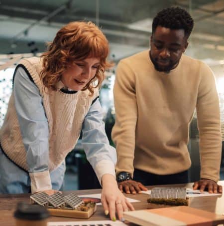 Portrait of smiling multicultural eco conscious staff standing at modern workspace and collaborating on global warming solution. Diverse colleagues discussing and analyzing data on charts and graphs.
