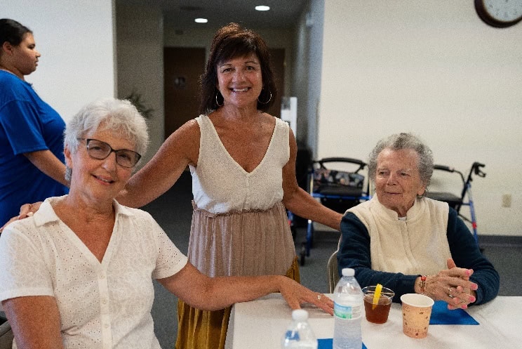 Women sitting at a table together smiling at the camera