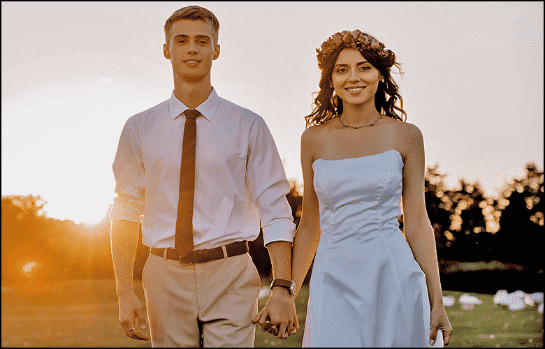 A man in a white shirt and tie holds hands with a woman in a white dress and floral headpiece, standing outdoors at sunset, as new wedding songs play softly in the background.