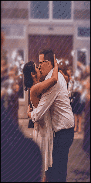 a man and a woman kissing in front of a building.