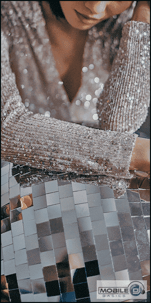 a woman in a sequined dress looking at her cell phone.