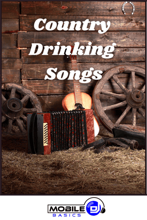 An accordion, guitar, and wagon wheels rest on hay in front of a wooden wall with the text "Country Drinking Songs" above them, setting the perfect scene for classic drinking songs.