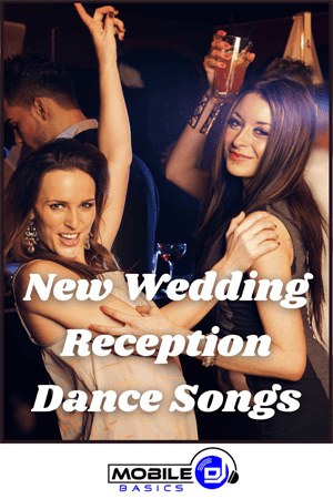 Two women dancing and smiling at a party with drinks in hand. Text overlay reads, "New Wedding Songs & Reception Dance Hits." Mobile Basics logo at the bottom.