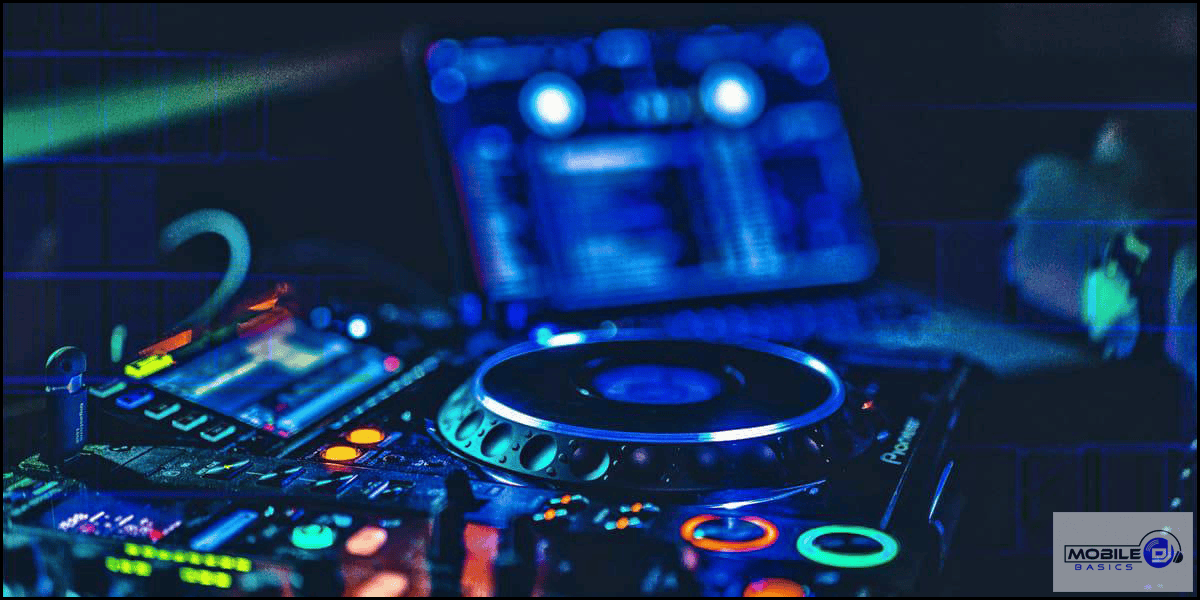 Close-up of a DJ controller and mixer with colorful illuminated buttons, perfect for learning Mobile DJ Basics, with a blurred laptop screen displaying audio software in the background.