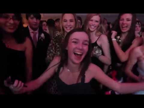 A group of young people dressed formally, smiling and laughing at what appears to be a Winter Formal or dance event.