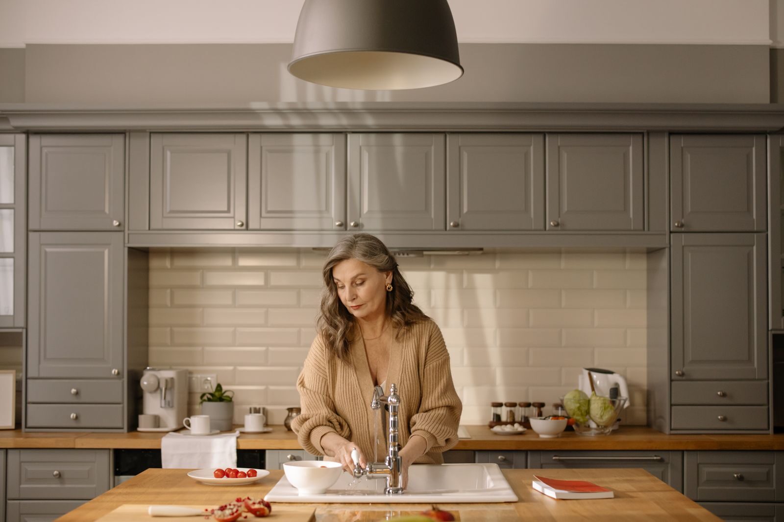 Senior woman at kitchen sink preparing ingredients amidst a modern setting, for cooking.