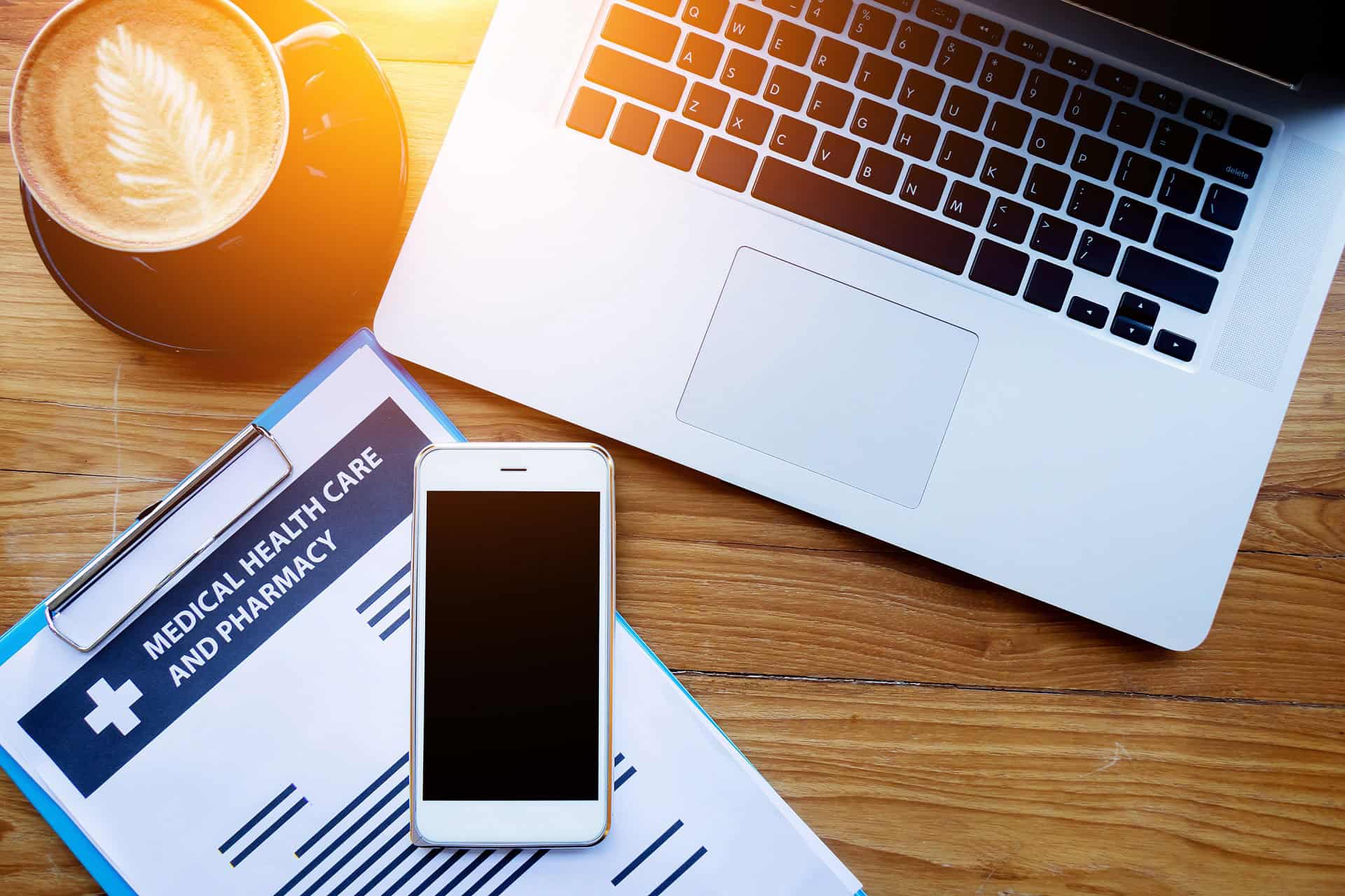 Desk top with cell phone laptop and forms reading health insurance