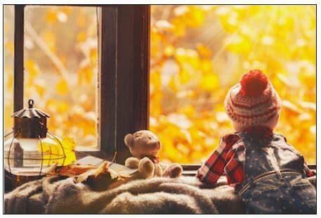 Child in winter hat looking out window