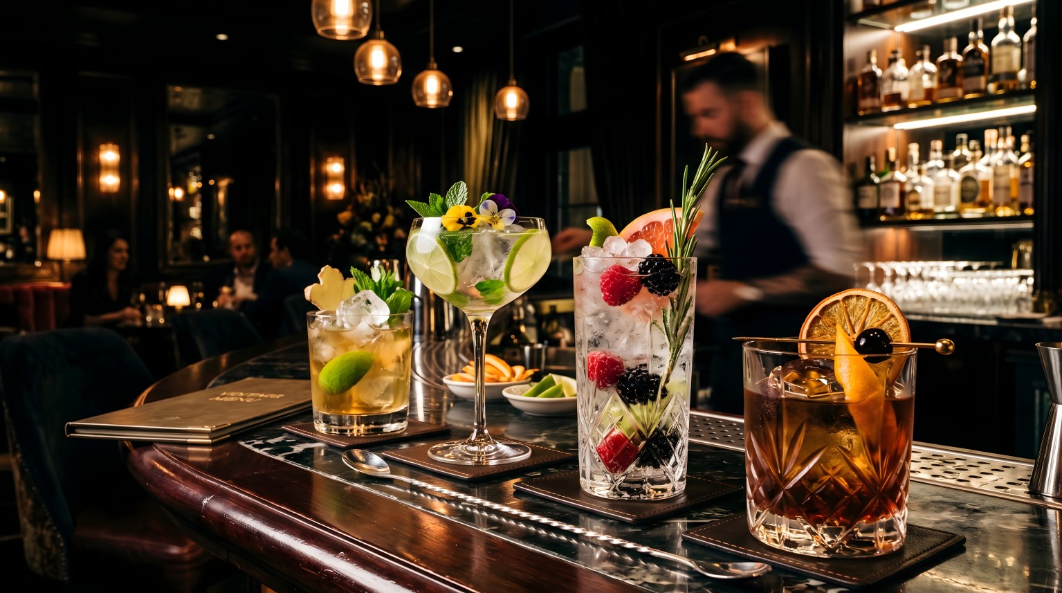 Craft cocktails with fruit garnishes lined up on a dark wooden bar counter