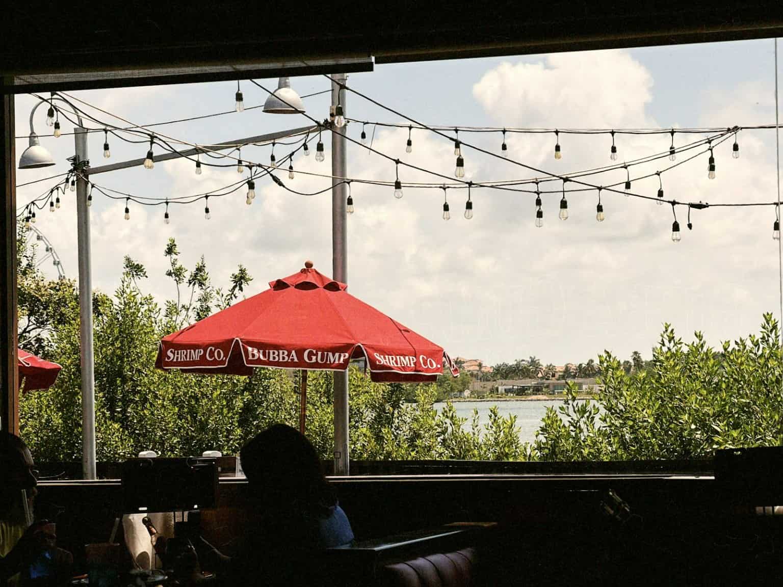 Restaurant patio with string lights, red umbrella, and lake view