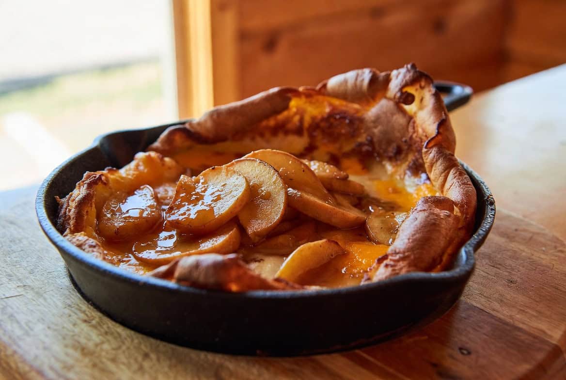 Puffy apple cheddar Dutch baby pancake in cast iron with caramelized apples