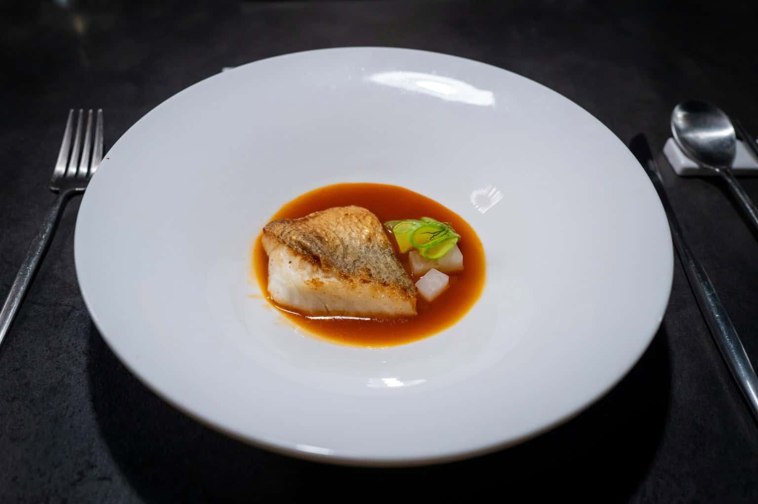 Glazed fish fillet on a white plate with sauce, plated for service