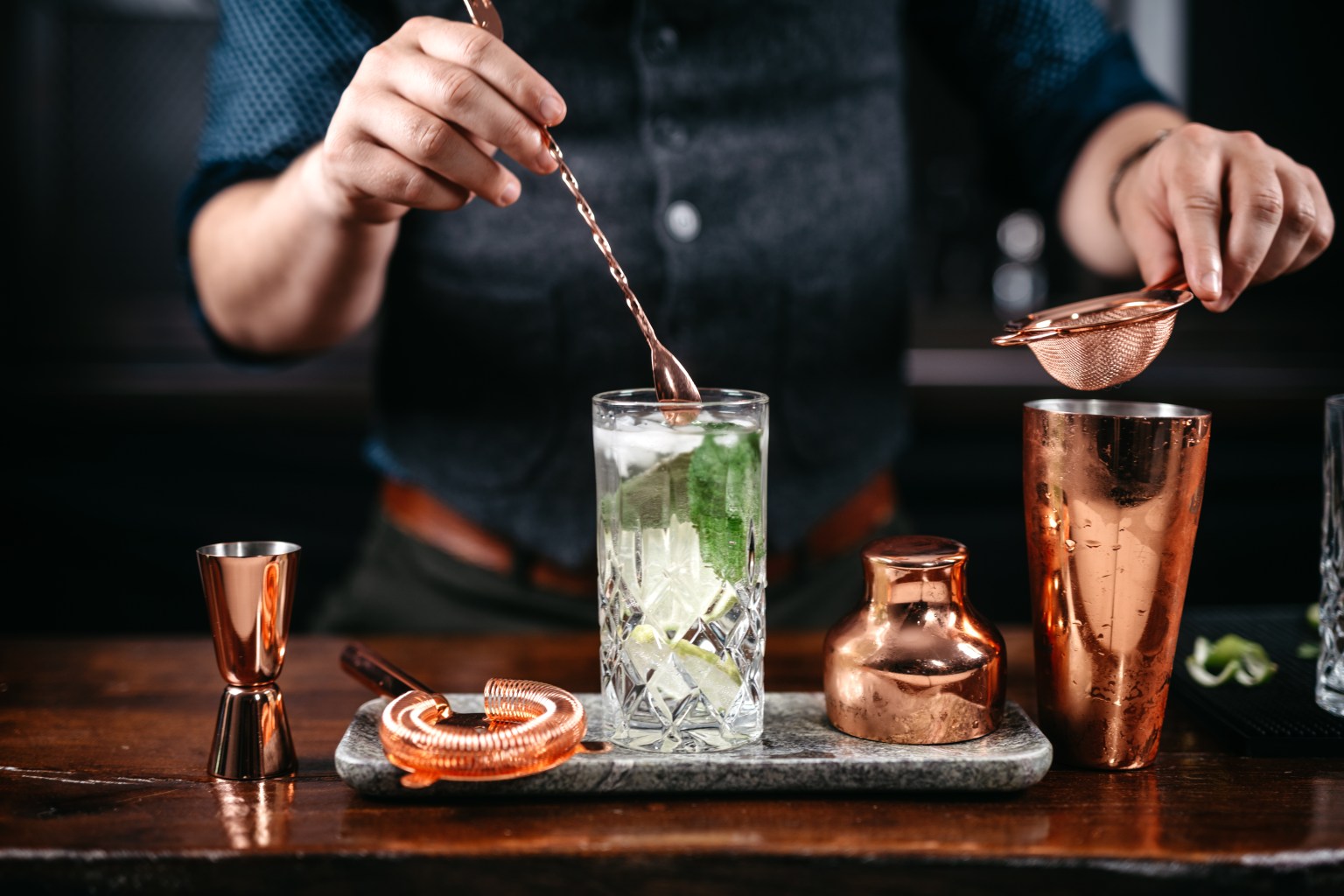 Bartender preparing a mojito with lime at a bar counter