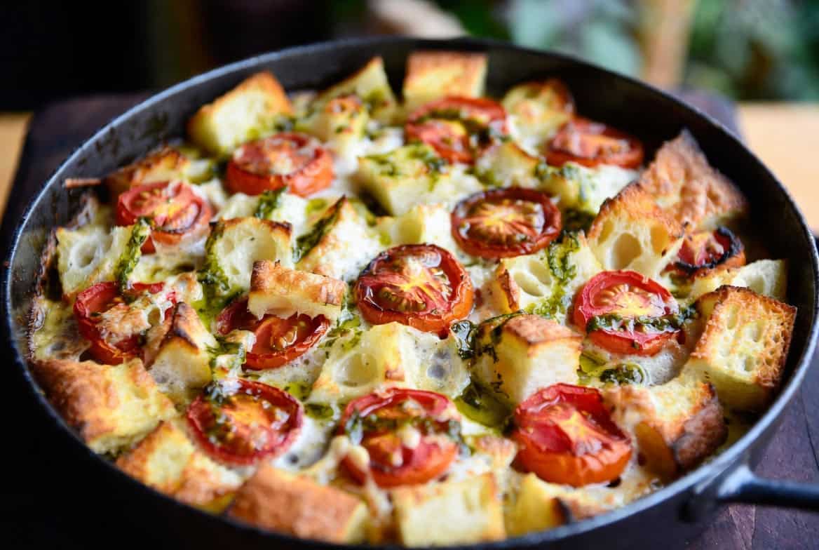 Golden tomato bread gratin in cast iron with herb oil