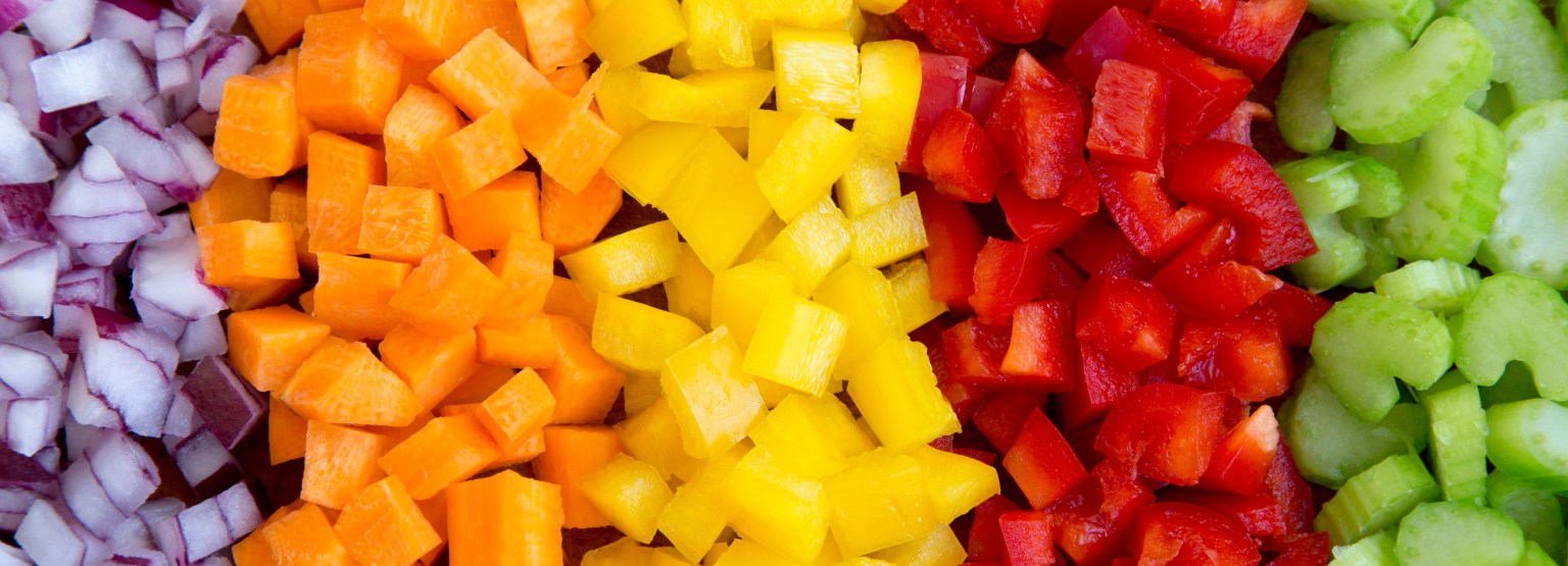 Chopped carrot, celery, red onion and peppers arranged on a cutting board
