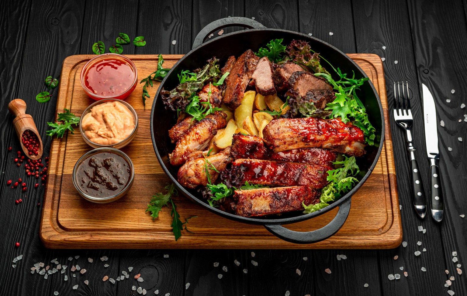 Different barbecue meat with potatoes in a frying pan