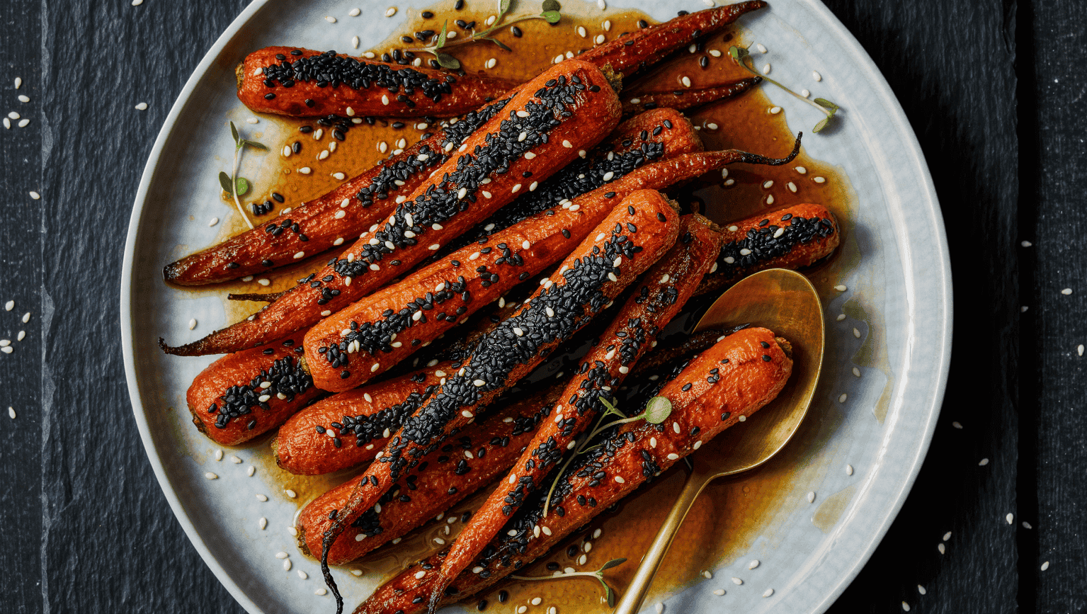 Roasted carrots glazed with maple and brown butter and rolled heavily in black sesame seeds so they read almost soot black