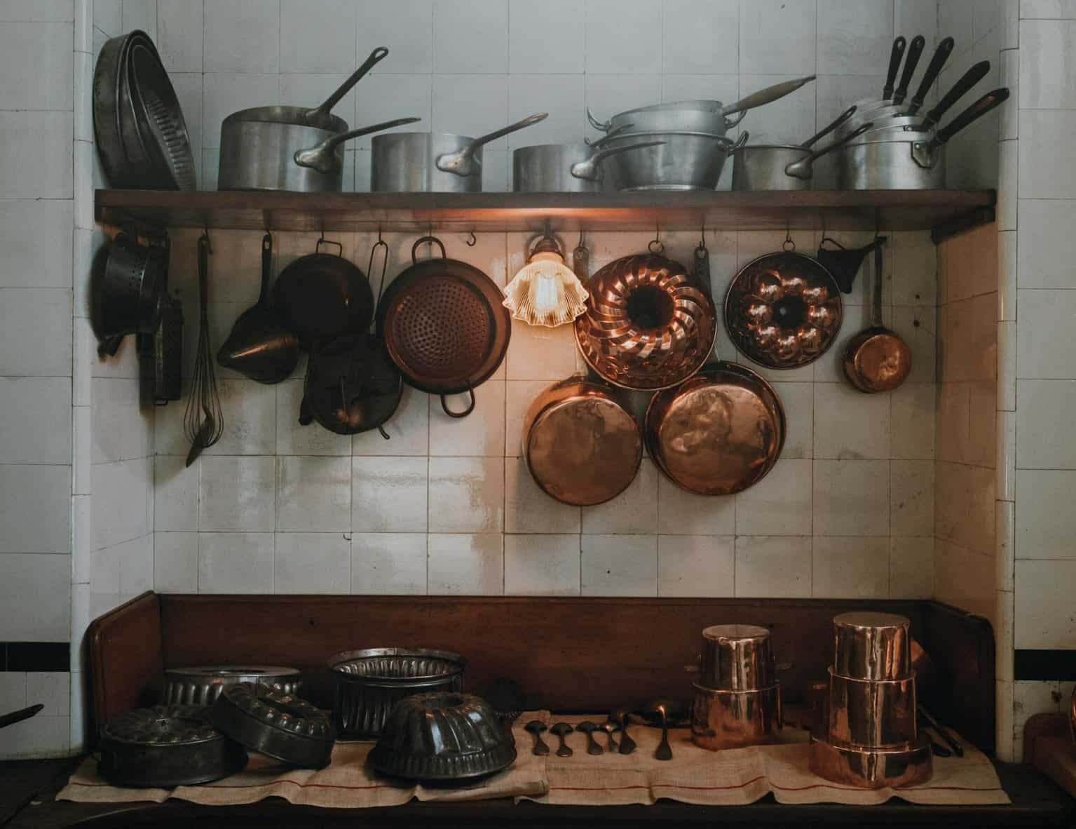 Copper pots and pans hanging in a warm vintage kitchen