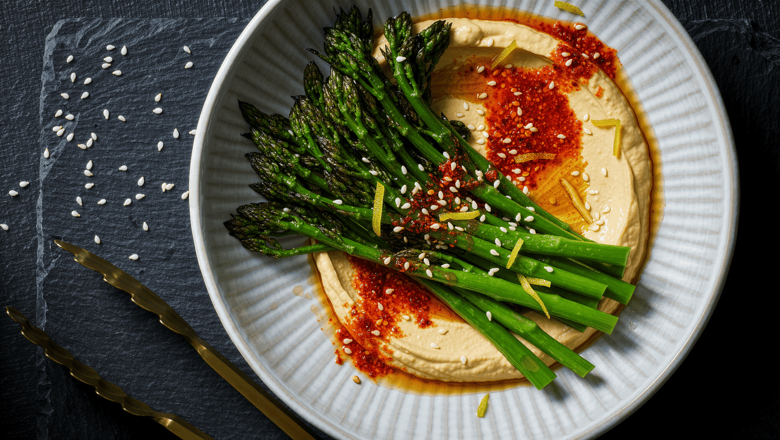 Charred broccolini piled over a swoosh of lemon tahini and spooned with red chile crunch oil, scattered with sesame seeds