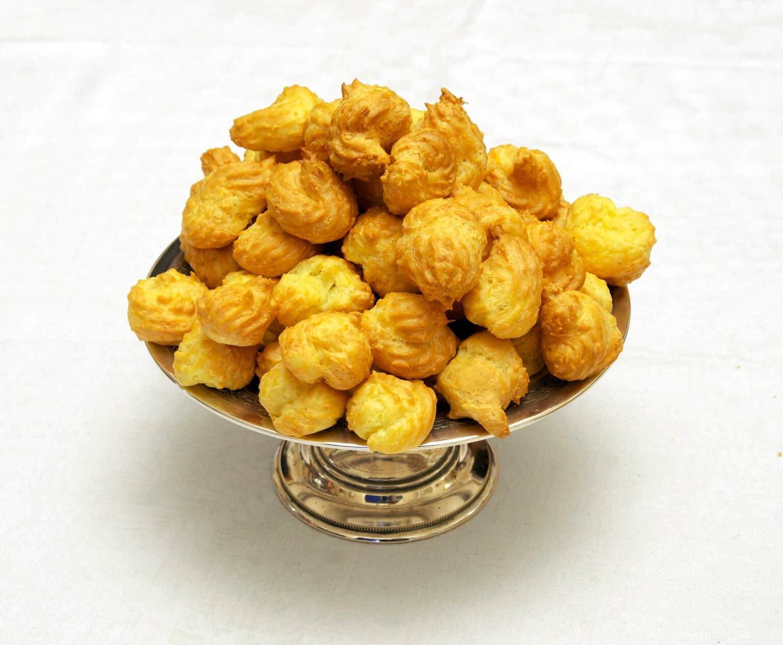 A silver dish piled with small golden cheese gougères