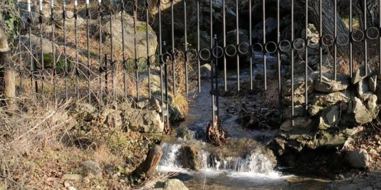Речна вода преминава през метална ограда в района на Алпийския дом в Природен парк „Сините камъни“.