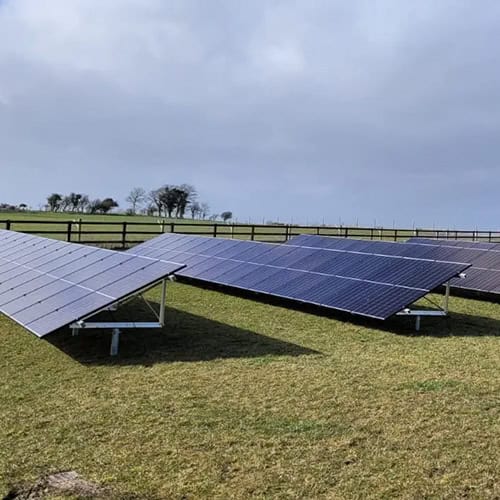 A row of solar panels on a grassy field.