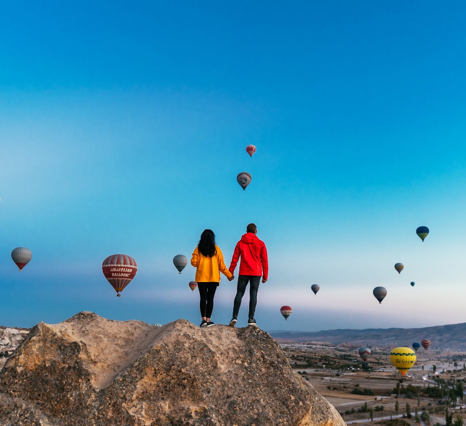Couple in love among balloons. Happy couple in Cappadocia. Honeymoon in the mountains. Man and woman traveling. Flying on balloons. Festival of balloons