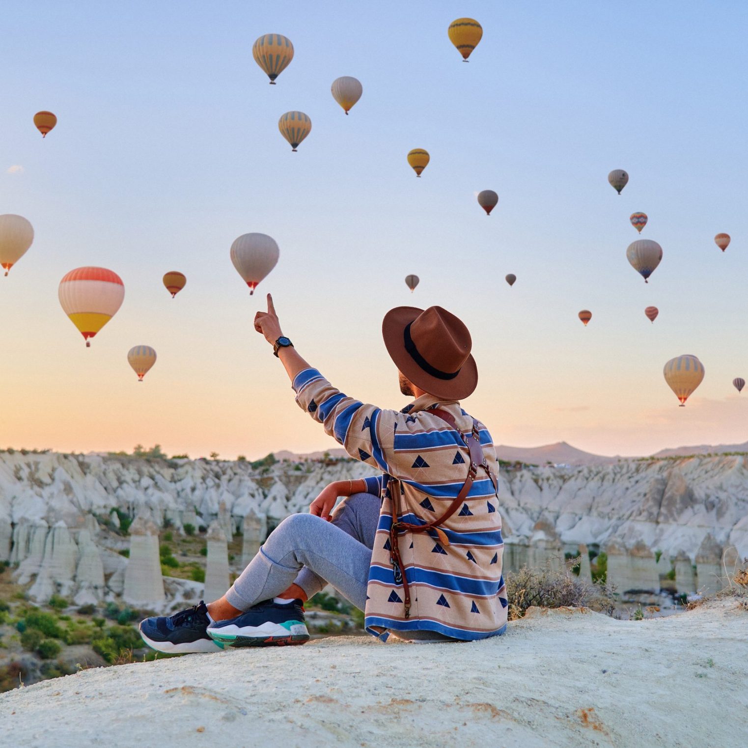Man traveler vacations beautiful destination in Goreme, Turkey. Fabulous Kapadokya with flying air balloons at sunrise, Anatolia