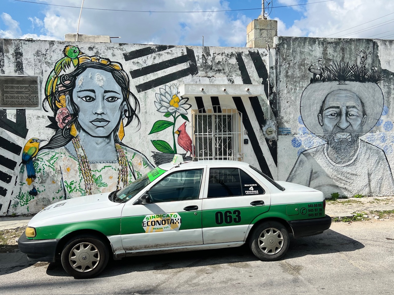 A taxi parked in front of a wall mural in Merida Mexico