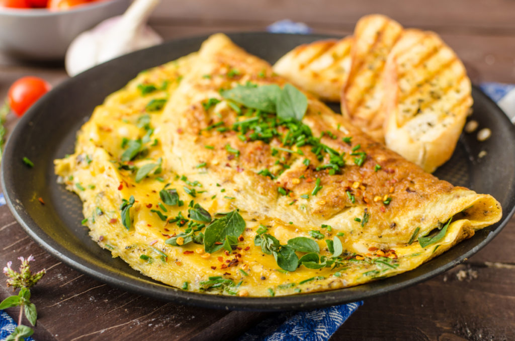 Herb omelette with chives and oregano sprinkled with chili flakes gruyere cheese and avocado on the side
