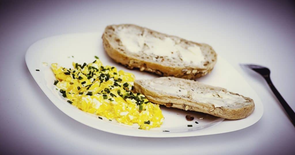 A picture of scrambled eggs and wheat bread, a good source of protein and vitamins for building muscle.